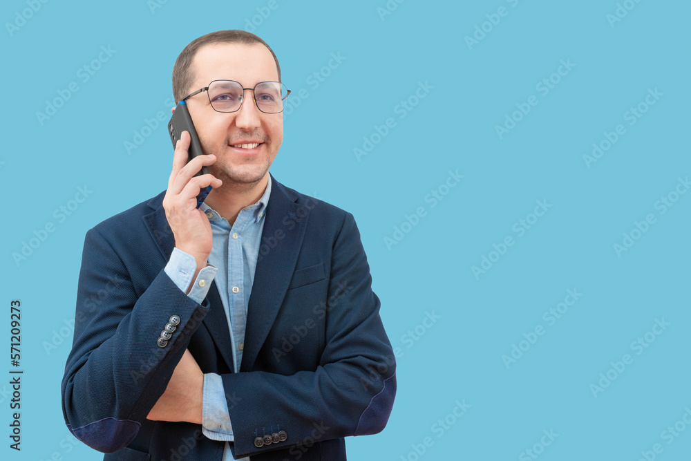 Young business man talking on a smartphone on a blue background in the studio. Young business man talking on a smartphone on a blue background in the studio.