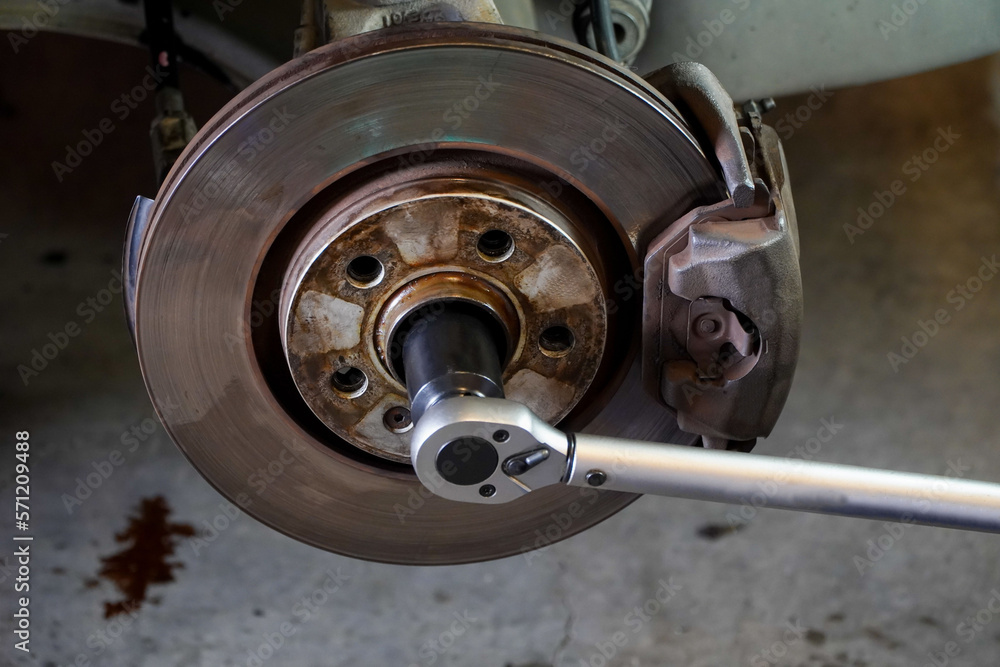 mechanic uses a pound wrench to tighten the car brake disc.car brake disc assembly mechanic uses a pound wrench to tighten the car brake disc.car brake disc assembly