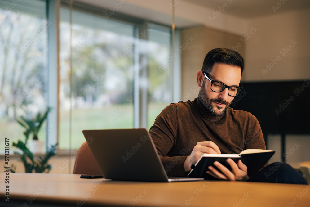 Focused male employer taking notes, witting in front of the laptop at the office. Focused male employer taking notes, witting in front of the laptop at the office.