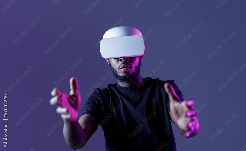 African American guy in Smart glasses of virtual reality. Augmented reality game, future technology, AI concept. VR. Neon light. African American guy in Smart glasses of virtual reality. Augmented reality game, future technology, AI concept. VR. Neon light.