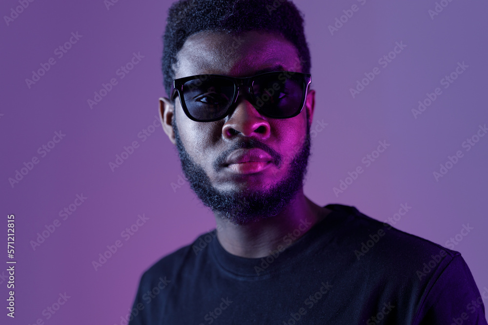 Stylish african american man in sunglasses and on dark neon background. Stylish african american man in sunglasses and on dark neon background.