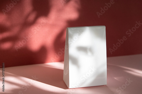 Gift wrapping on a red background. Gift with empty space for text. Box mockup for design. Background with sunlight and shadows.
