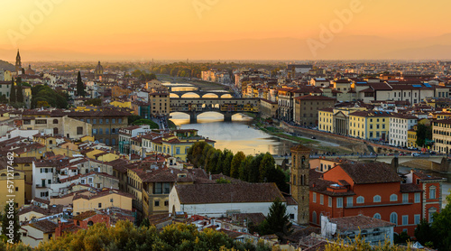 The Florence cityscape with the Ponte Vecchio over Arno river in an orange sunset.