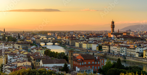 Fototapeta Naklejka Na Ścianę i Meble -  The Florence cityscape with the Ponte Vecchio over Arno river and Palazzo Vecchio in an orange sunset.