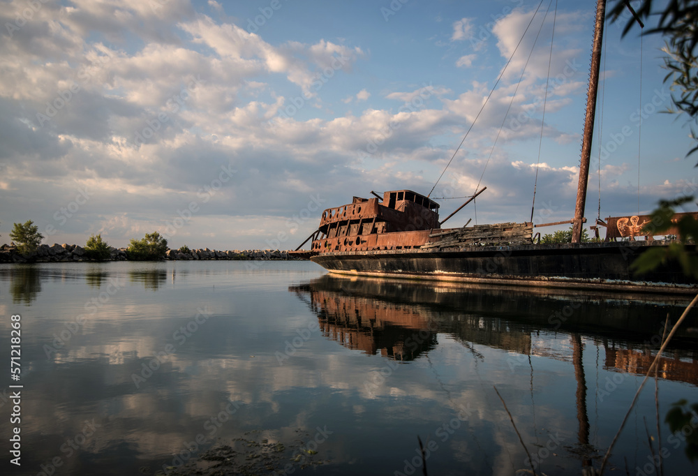 Fototapeta premium A rusty hulk of a sinking ship in the harbor