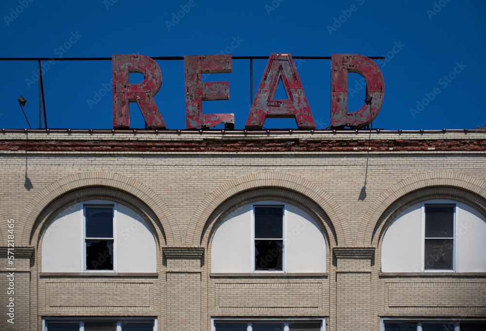 Obraz premium Old large red letters on the roof of an abandoned factory, spelling READ