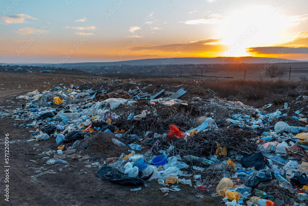 Urban garbage in polluted field at sunset. Environmental concept.