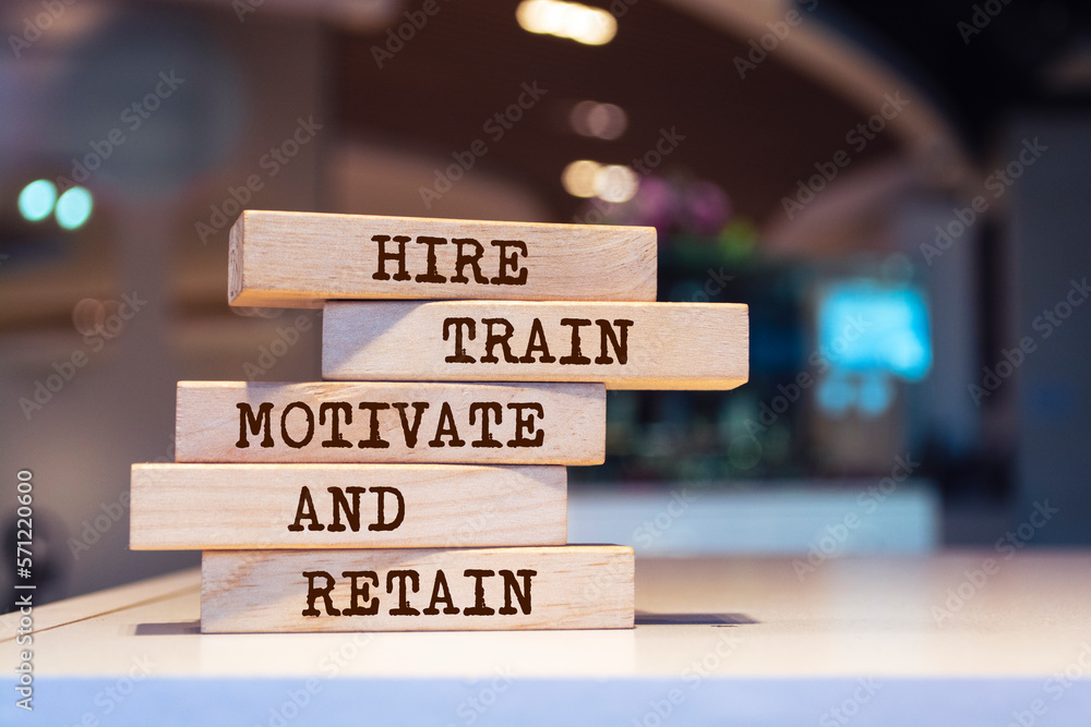 Wooden blocks with words 'Hire, Train, Motivate and Retain'.