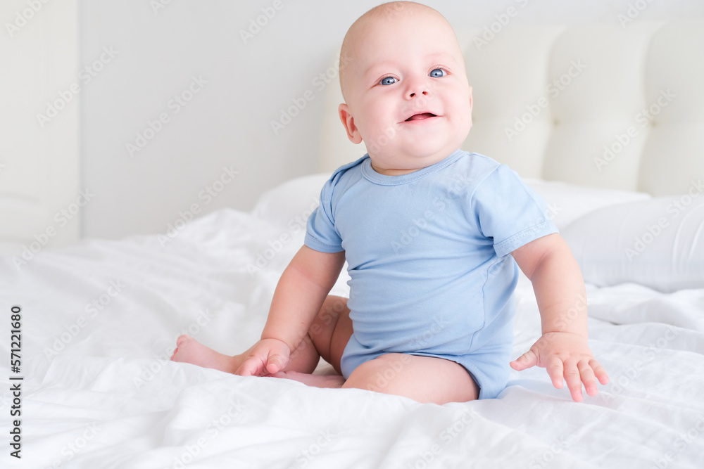 portrait of smiling baby boy with big blue eyes in bodysuit on white bedding. Healthy newborn child portrait of smiling baby boy with big blue eyes in bodysuit on white bedding. Healthy newborn child