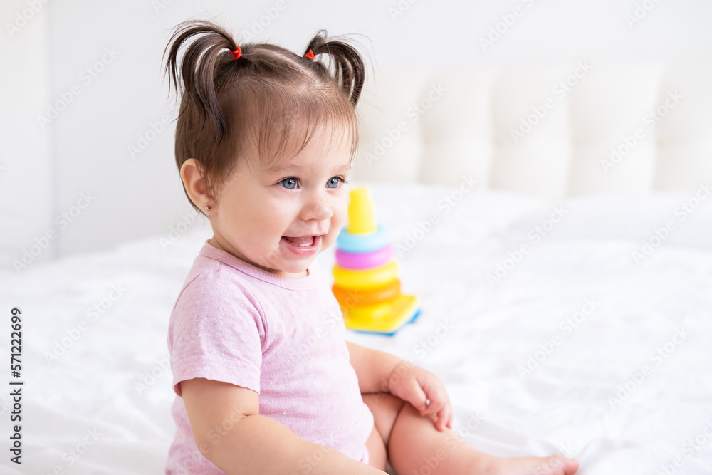 portrait of smiling baby girl in pink bodysuit with 2 tails on bed portrait of smiling baby girl in pink bodysuit with 2 tails on bed