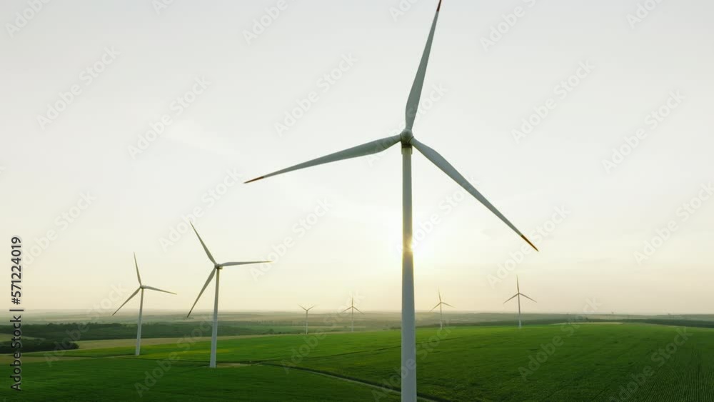 Large wind turbines with blades in field aerial view bright orange sunrise pink orange sky wind park green grass slow motion drone turn. Silhouettes windmills summer. Alternative energy. Nature Large wind turbines with blades in field aerial view bright orange sunrise pink orange sky wind park green grass slow motion drone turn. Silhouettes windmills summer. Alternative energy. Nature