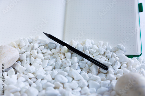 Notebook and pen on white studio background. White rocks falling in front of it. Beautiful composition of notebook, pen. High quality photo