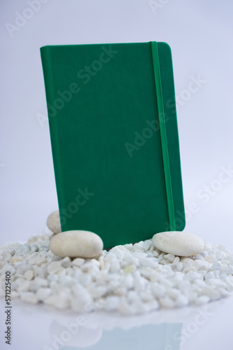 Green notebook on a mountain stack of white rocks. Beautiful studio product photoshoot. High quality photo