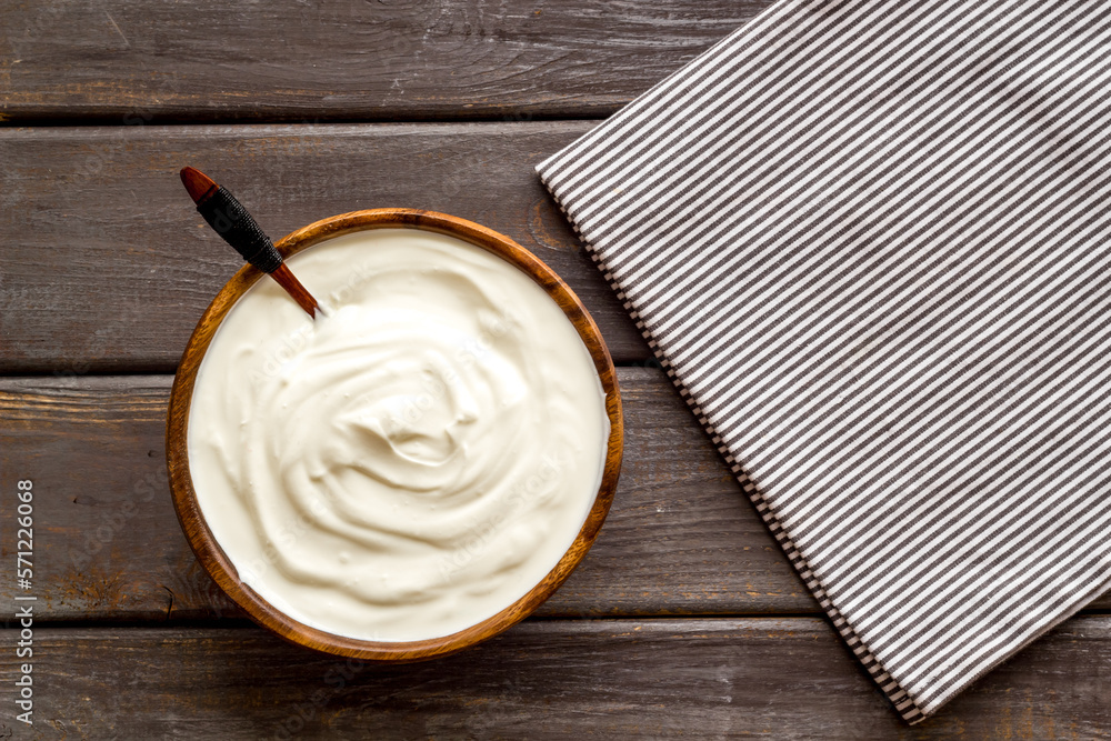 White sauce sour cream or yogurt in wooden bowl, top view White sauce sour cream or yogurt in wooden bowl, top view
