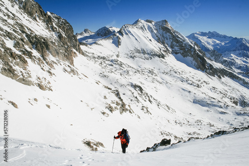 Snow hiker walking on snow with the view of the mountains and blue sky in the background © raulbachiller