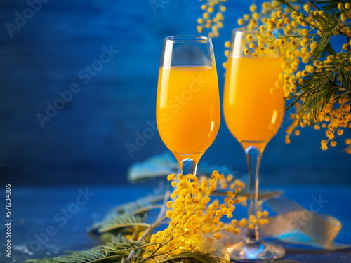 Mimosa cocktail with flowers on a blue background. Copy space