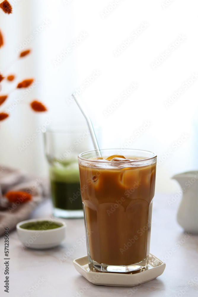 Close up of a cup of iced coffee with milk, milk jug, matcha powder and a cup of matcha green tea in the afternoon sun on table.
Iced coffee and green matcha on a light blurred background. Food trend
Close up of a cup of iced coffee with milk, milk jug, matcha powder and a cup of matcha green tea in the afternoon sun on table.
Iced coffee and green matcha on a light blurred background. Food trend