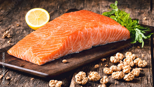 big raw salmon piece decorated with some wallnuts lemon and parsley laying on an old wooden table as natural source of omega-3 and proteins, generative AI