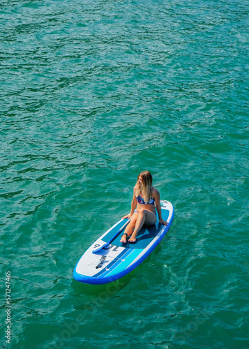 SUP Stand up paddle board. Blond girl rest on paddle board in sea. Aerial view. Woman on summer holidays vacation lifestyle. Mtsvane Kontskhi Beach, Batumi, Georgia. © Khrystyna Bohush
