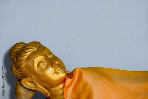 The golden Buddha is sleeping peacefully and smiling, lying under a blanket