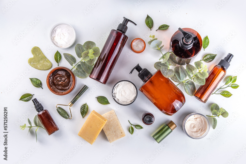 Natural organic skin care flat lay. Natural organic beauty cosmetic products on white background: hand lotion, face cream in jar, essential oil, skin roller, with eucalyptus and tea tree leaves - obrazy, fototapety, plakaty 