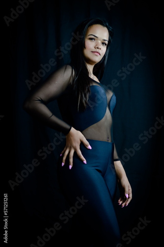Portrait of a beautiful young Brazilian woman with one hand on her hip, dressed in a black sheer bodysuit