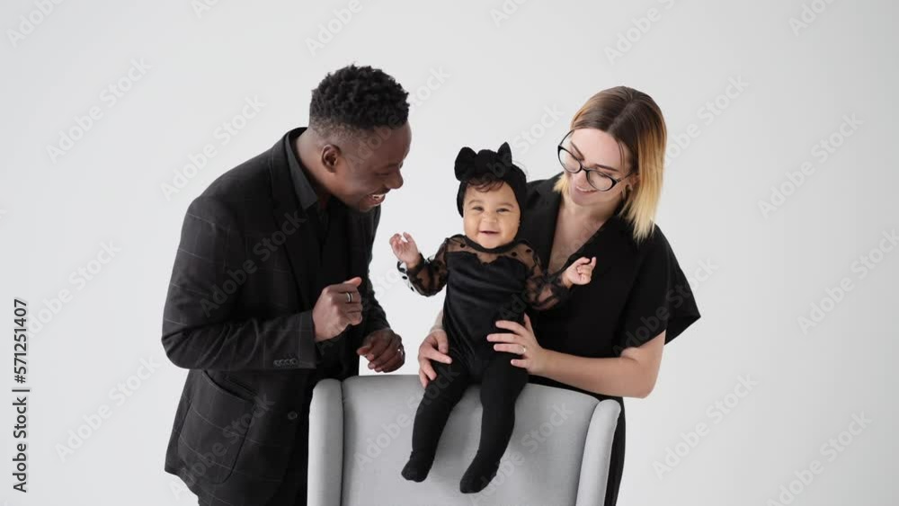 Happy interracial family with baby daughter has fun and plays near armchair. Happy interracial family with baby daughter has fun and plays near armchair.