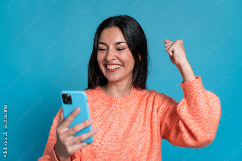 Smiling woman with smartphone celebrating good news