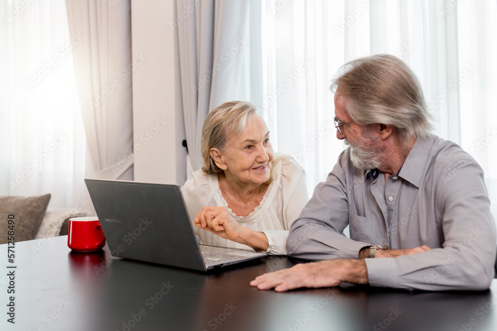 Happy Caucasian 70s mature couple using laptop at home. Old people using computer at home. Senior man and woman surfing the web on a wireless laptop connection. Modern retired lifestyle people. Happy Caucasian 70s mature couple using laptop at home. Old people using computer at home. Senior man and woman surfing the web on a wireless laptop connection. Modern retired lifestyle people.