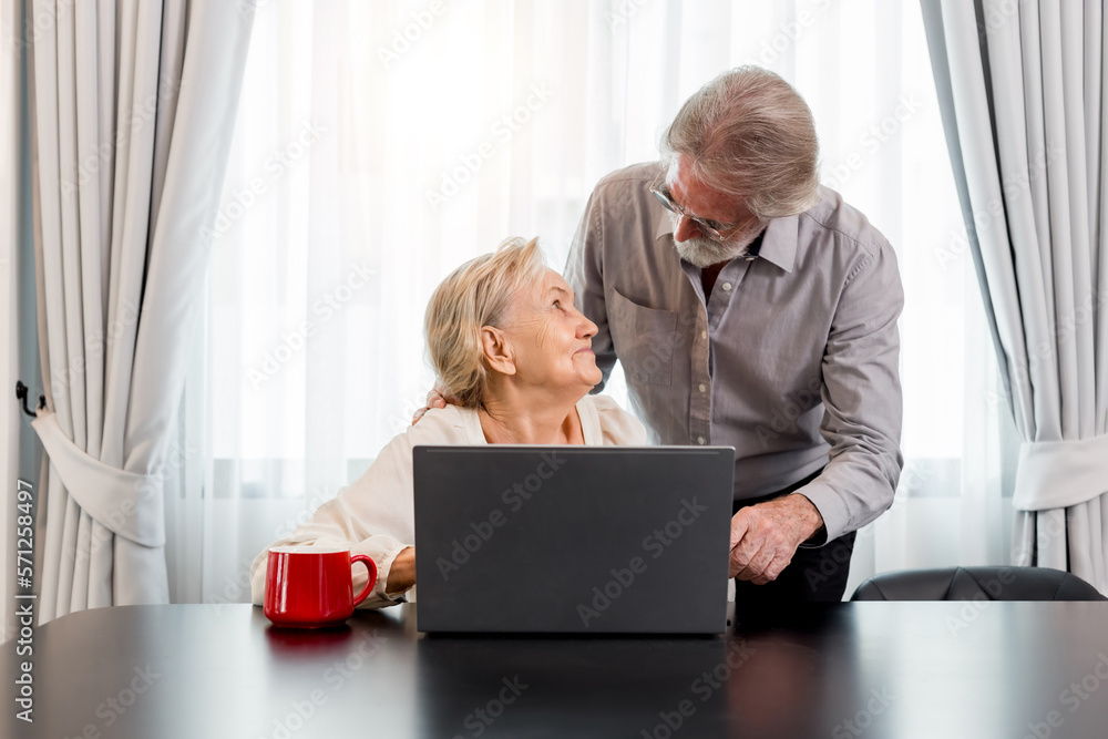 Happy Caucasian 70s mature couple using laptop at home. Old people using computer at home. Senior man and woman surfing the web on a wireless laptop connection. Modern retired lifestyle people. Happy Caucasian 70s mature couple using laptop at home. Old people using computer at home. Senior man and woman surfing the web on a wireless laptop connection. Modern retired lifestyle people.