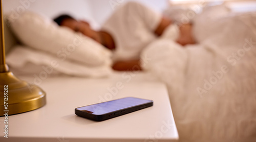 Man At Home Asleep In Bed With Alarm Going Off On Mobile Phone