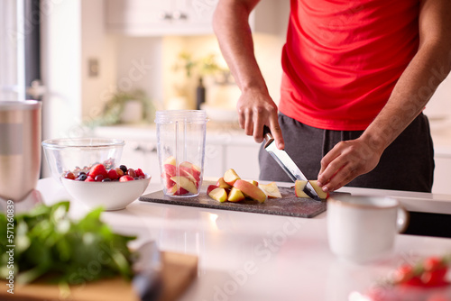 Close Up Of Man In Kitchen Wearing Fitness Clothing Blending Fresh Ingredients For Healthy Drink