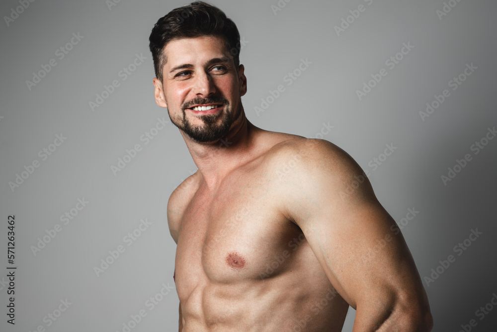 Fototapeta premium Portrait of a handsome young man with stylish haircut posing over gray background. Perfect body&skin. Studio shot.