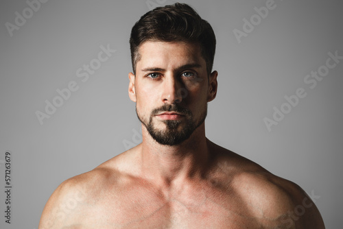 Portrait of a handsome young man with stylish haircut posing over gray background. Perfect body&skin. Studio shot.