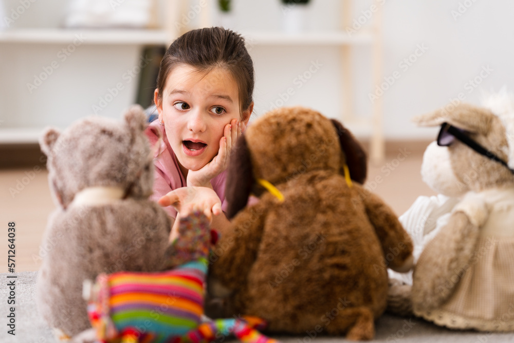 Little girl talking to fluffy toys lying down on floor Little girl talking to fluffy toys lying down on floor