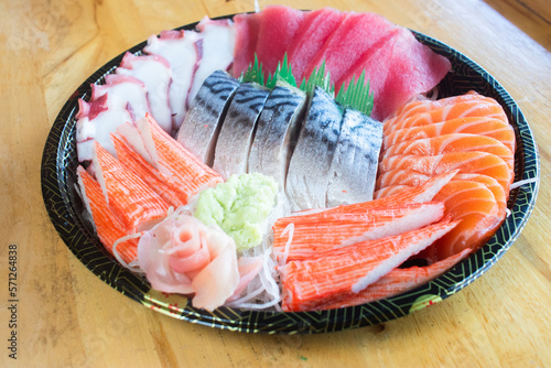 Assorted sashimi on a Japanese patterned tray It consisted of fresh tuna, fresh salmon, taco tentacles, crab sticks and mackerel, garnished with wasabi and pickled ginger.