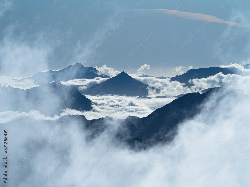 Alpine cloudscape nature panorama mountain peaks peeking through clouds seen from Brewster Hut Southern Alps New Zealand