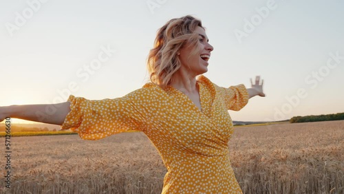 Joyful young woman spinning turn with happiness nature smiling in wheat field at orange sunset in summer looking at camera closeup. Rest from city life. Reloading people among nature. Relax. Lifestyle
