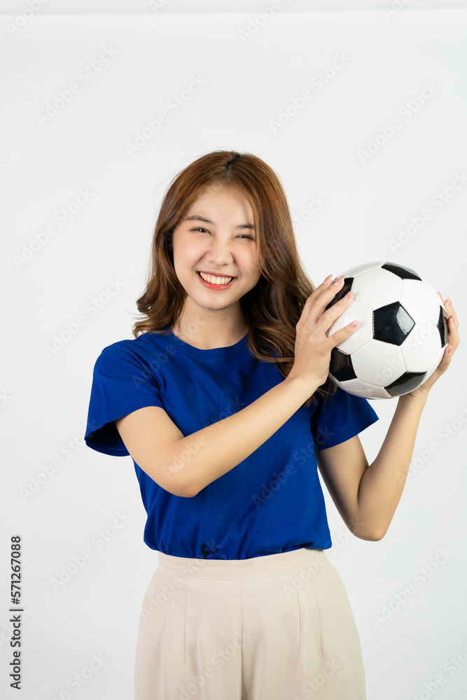 Happy Asian female soccer fan in blue shirt cheering for favorite team with soccer ball isolated on white background, pretty young pretty girl holding soccer ball, sports concept Happy Asian female soccer fan in blue shirt cheering for favorite team with soccer ball isolated on white background, pretty young pretty girl holding soccer ball, sports concept