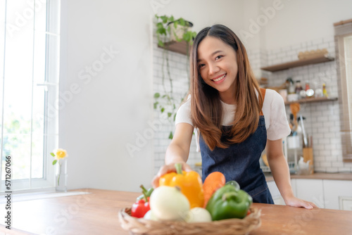 Pretty Asian woman preparing healthy breakfast at home in modern and beautiful kitchen  smiling brightly.