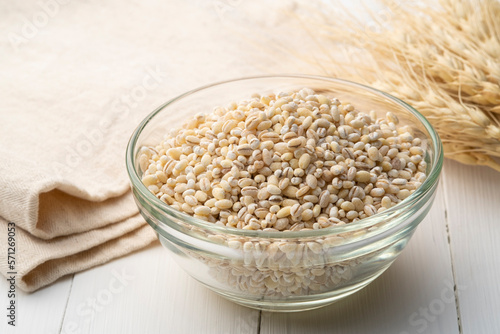 Uncooked barley, pearl barley in glass bowl on wood table