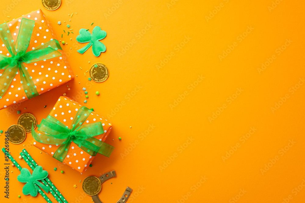 St Patrick's Day concept. Top view photo of present boxes with green ribbon bows sprinkles trefoils gold coins horseshoe and straws on isolated orange background with copyspace