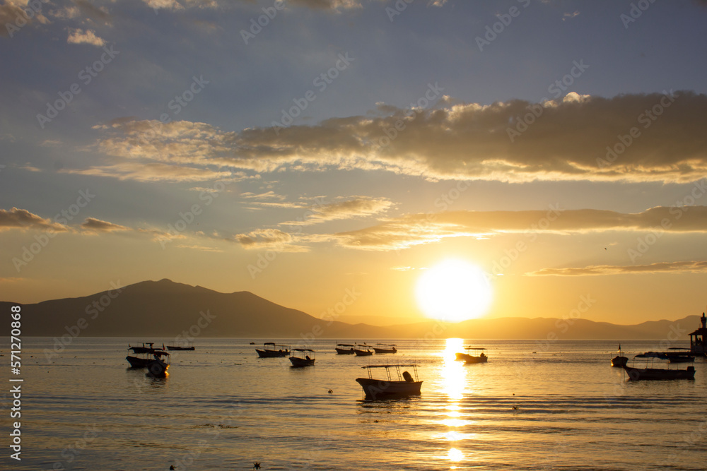 Boats floating on a lake at sunset