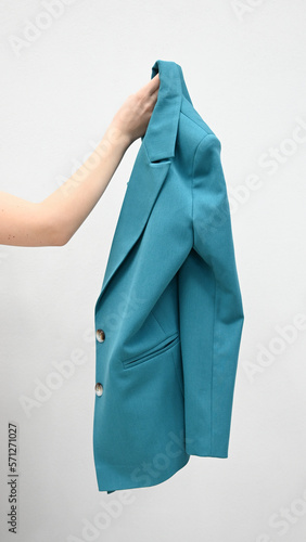Woman holding a jacket in her hand on white background. Cropped view of famale hand and stylish jacket isolated.Vertical