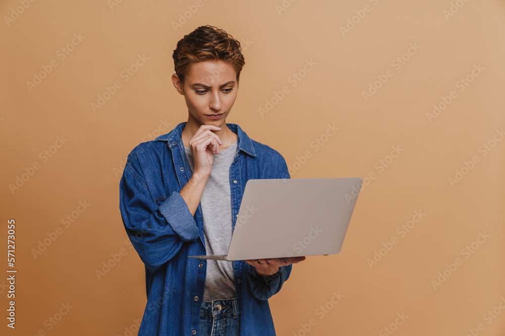 Portrait of young short-haired beautiful thoughtful woman holding laptop Portrait of young short-haired beautiful thoughtful woman holding laptop