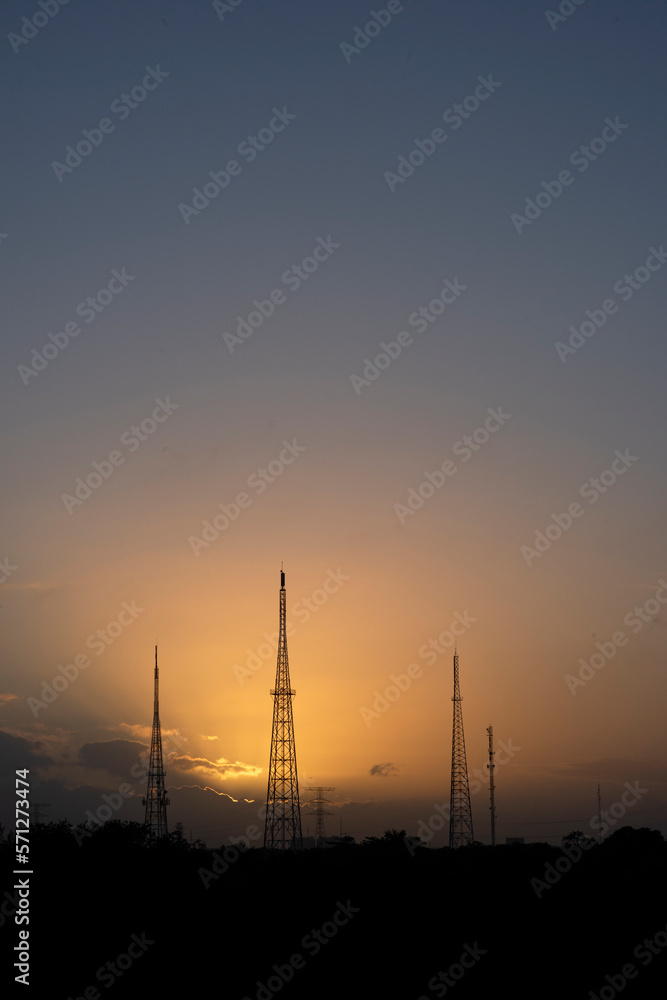 Silhouette high voltage steel pylons at sunset, vertical image in Mexico