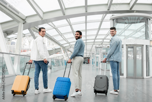 Group Of Male Tourists Walking With Suitcases Posing In Airport