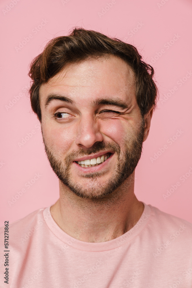 Cheerful man winking and looking aside while posing isolated over pink wall Cheerful man winking and looking aside while posing isolated over pink wall