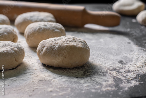 raw bread with rolling pin and scattered flour on black table