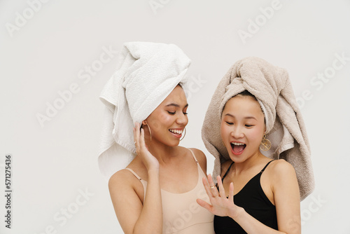 Two smiling women posing isolated over white wall